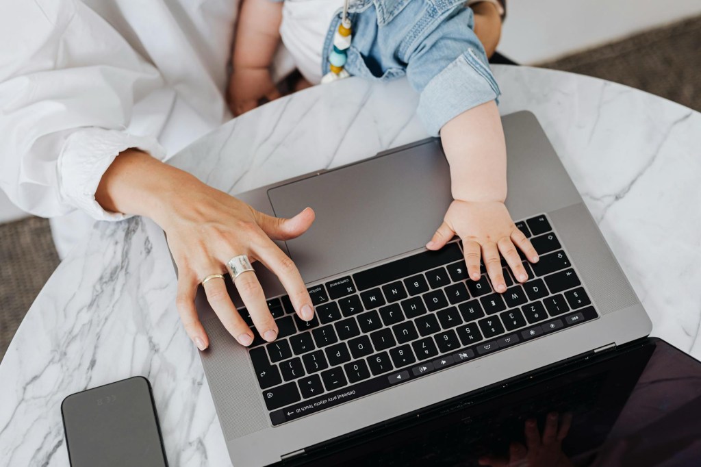 Mother’s hand and child’s hand pressing on a laptop keyboard